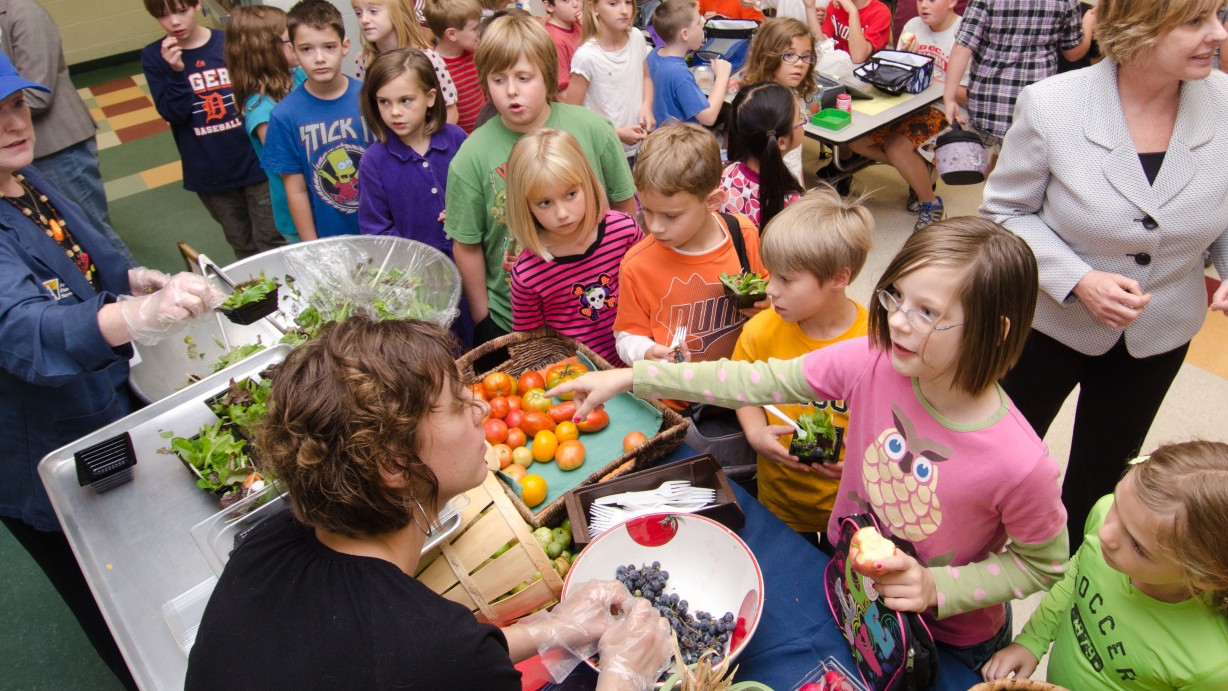 Registered Dietician Sandra B. O'Connor prepared and served sample mixed greens salads, while Maple Avenue Market Farm co-owner Sara Guerre (bottom l.) invited students to learn about local and interesting varieties of produce such as purple corn on the cob that is used for popping, during a National School Lunch Week event at Nottingham Elementary School in Arlington, VA, on Wednesday, October 12, 2011. Farmers from Bigg Riggs Farm in Hampshire County, WV, and Maple Avenue Market Farm in Vienna, VA were very popular with the students. Today's menu included roasted chicken, roasted butternut squash with dried cranberries, farm fresh mixed lettuce salad, turkey wraps, pita wedges, hot muffins, carrots, Asian pears and more.  USDA Photo by Lance Cheung.